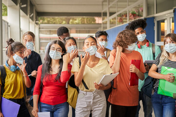 Group of students putting on or taking off their face masks. Young people of various ethnicities take safety measures against the covid virus. Back to school.
