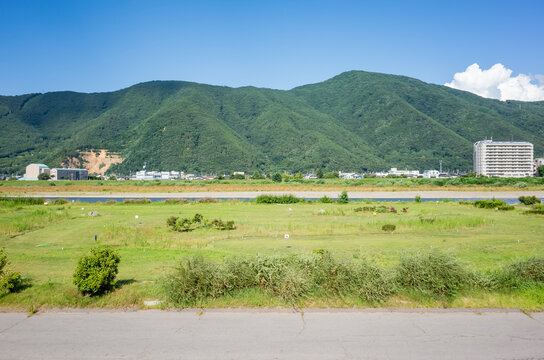 summer natural scenery seen from riverside road; mountain range and chikuma river in nagano prefecture, japan