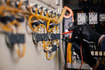 Obraz premium Electrician engineer work tester measuring voltage and current of power electric line in electical cabinet control.and wires on relay protection system. Bay control unit. Medium voltage switchgear.