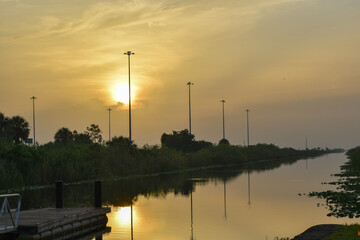 Fototapeta na wymiar Huge orange sun reflecting in the swamp at sunrise