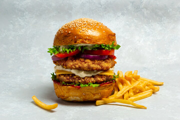 Fresh Big breaded chicken burger with double cutlet and fries on light grey background. Fat...