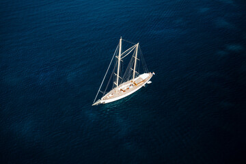 View from above, stunning aerial view of a luxury sailboat sailing on a blue water during a sunny day. Costa Smeralda, Sardinia, Italy
