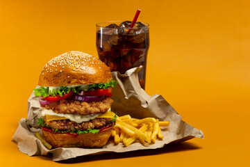 Fresh Big chicken burger with double cutlet, fries and cola on craft paper. Fat unhealthy street...