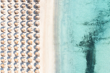 Stunning aerial view of some beach umbrellas on a white sand beach bathed by a turquoise water...