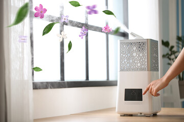 Woman switching on modern humidifier in room