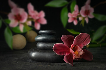 Stack of spa stones and beautiful flowers on dark background