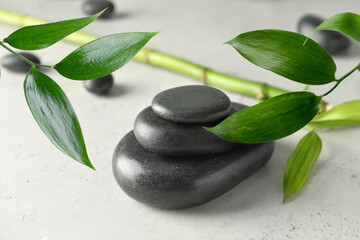Stack of spa stones and bamboo on light background