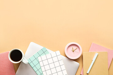 Alarm clock with office supplies, cup of coffee and laptop on color background