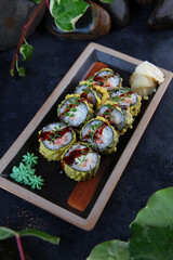 Japanese rolls in batter. Rolls in tempura with smoked salmon and green onions. Traditional Japanese cuisine. Vertical photo. View from above. Out of focus.