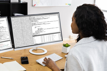African Coder Using Multiple Computer Screens