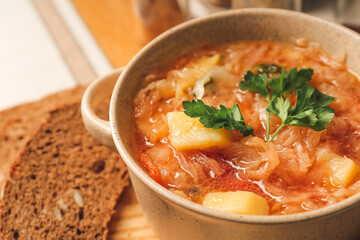 Pot with tasty sauerkraut soup on table, closeup