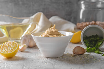 Bowl with tasty hummus and ingredients on table