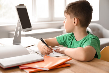 Naklejka na ściany i meble Little boy studying online at home