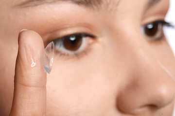 Fototapeta premium Young woman putting in contact lenses, closeup