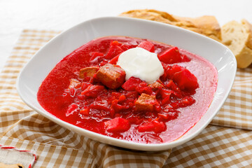 Bowl of tasty borscht with sour cream on light background