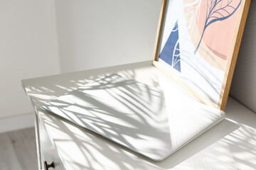 Modern laptop on table near light wall
