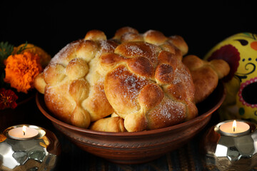 Bowl with bread of the dead on table against dark background. Celebration of Mexico's Day of the Dead (El Dia de Muertos)