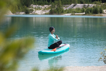 The girl does yoga on the glanders on the pond