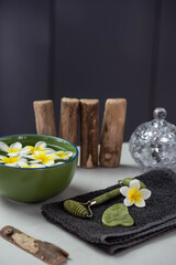 Beautiful spa composition with plumeria flowers. Face roller and guasha massager. Facial skin care, anti age products and creme. Chinese Gua Sha massage tools.