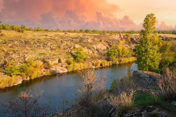 A large number of stone minerals covered with vegetation lying over a small river in picturesque Ukraine
