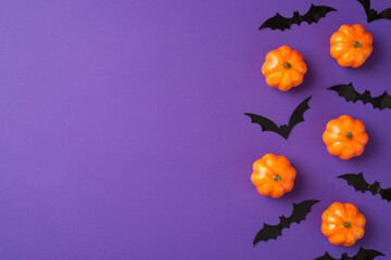 Top view photo of halloween decorations small pumpkins and bats silhouettes on isolated violet...
