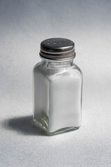 A pile of salt from salt shaker, concept excessive salt intake and white death