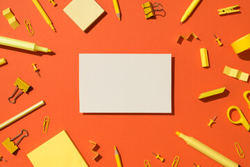 Top view photo of white card yellow stationery school accessories scissors pencils felt pens binder clips pins and sticky note paper on isolated vivid orange background with copyspace
