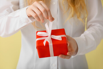 Young woman with gift on color background, closeup