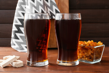 Glasses of fresh kvass and raisins on wooden background