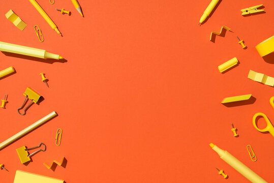 Top view photo of yellow stationery school supplies scissors pencils markers binder clips pushpins adhesive tape and sticky note paper on isolated vivid orange background with empty space