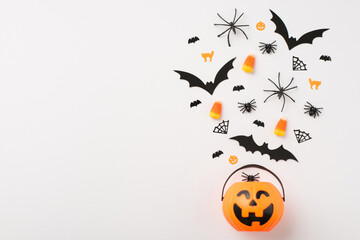 Above photo of pile of big and mini bats spiders cats candies as corn and basket with sweets as pumpkin isolated on the white background with blank space
