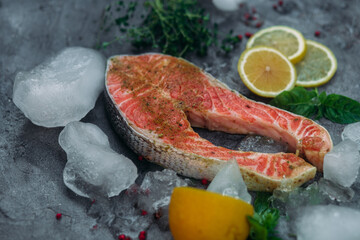 Raw salmon steak with herbs and lemon on gray background