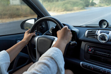 Female person drives a car with both hands on the steering wheel.Careful driving.Focus is on the steering wheel