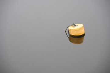 One yellow buoy floating in water for demarcation of safe water depth