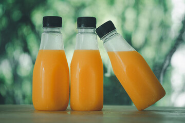 Three of fresh orange juice are in a bottles with black cap