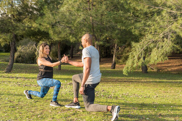 Obraz premium Fitness couple exercising by holding hands in the park