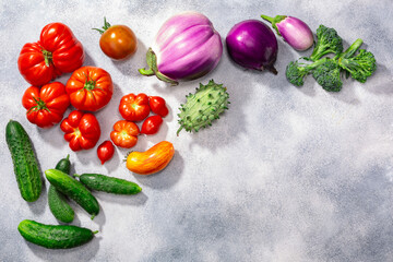 Fresh select seasonal  vegetables atop grey textured backdrop, top view, copy space