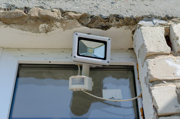 Motion sensor and LED spotlight on the wall of the building. Aut