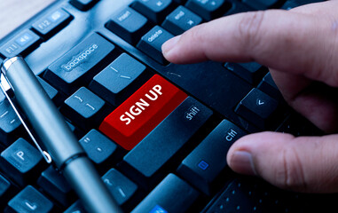 A finger pointing on a red computer keyboard written with Sign Up.