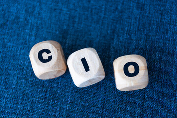 CIO written on wooden cubes - arranged in a vertical pyramid, grey and blue background, CIO - short for Chief Information Investment Officer, business concept - obrazy, fototapety, plakaty