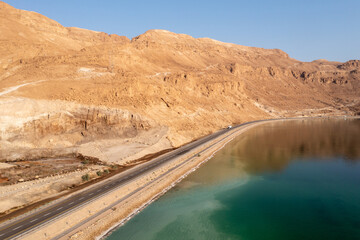 Dead Sea coastline and highway with desert mountains, Aerial view.
