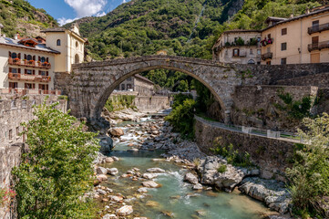 Fototapeta na wymiar The ancient Pont Saint Martin bridge, in the historic center of the homonymous village, on a sunny day, Aosta Valley, Italy