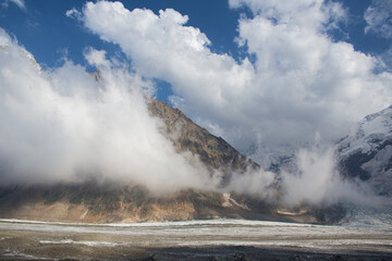 White beautiful clouds float against the background of high mountains.