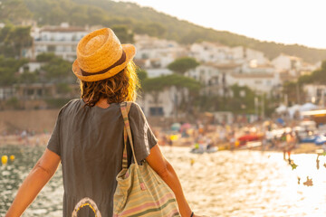 Fototapeta premium A young tourist with a hat at sunset on the coast of Tamariu in the town of Palafrugell. Girona, Costa Brava in the Mediterranean