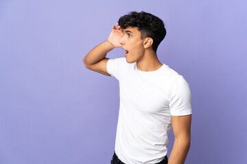 Young Argentinian man isolated on background with surprise expression while looking side