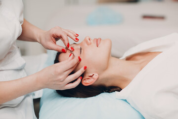 Beautiful young woman getting face treatment massage at beauty spa