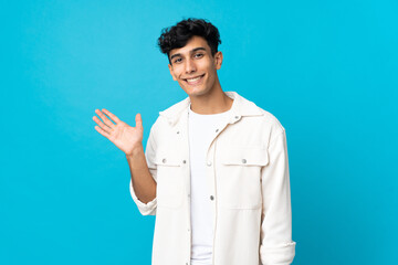 Young Argentinian man isolated on background holding copyspace imaginary on the palm to insert an ad