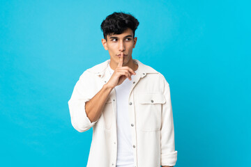 Young Argentinian man isolated on background showing a sign of silence gesture putting finger in mouth