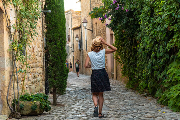 A tourist girl walking through the streets of Peratallada medieval town, historic center, Girona on...