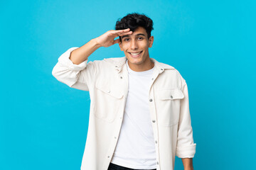 Young Argentinian man isolated on background looking far away with hand to look something